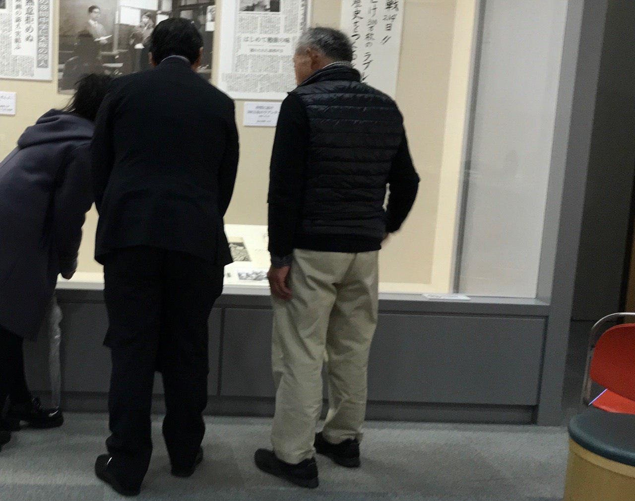 白井善吾（右）さんの案内で、「夜間中学生」展を見学する前川喜平さん（中）